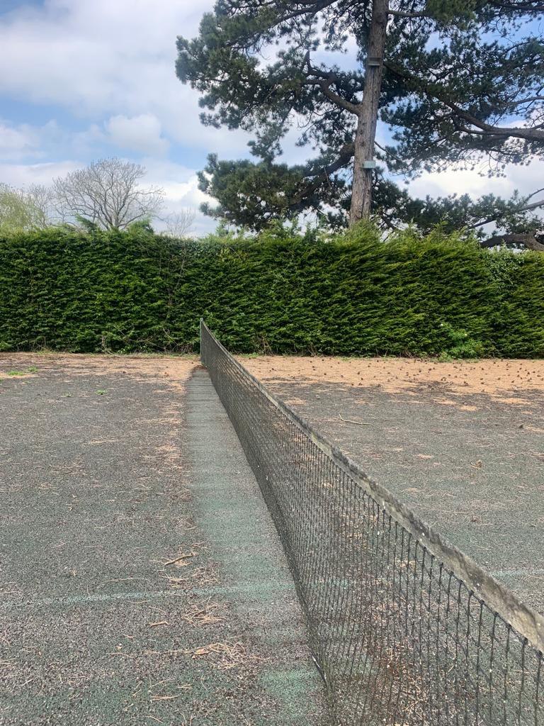 This is a photo of a tennis court in Dorset that is in need of refurbishment